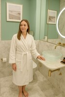 Un baño con lavamanos de mármol, un recipiente de vidrio, inodoro y un cuadro en la pared.