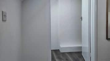 Een kamer met een dakraam, een deur naar een andere kamer en een donker houten vloer.