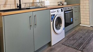 Una cucina funzionale con mobili grigi, lavatrice integrata, forno a microonde e lavello.