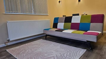 Een kamer met een bed, een radiator, een kamerbreed tapijt met een patroon en twee wandlampen.