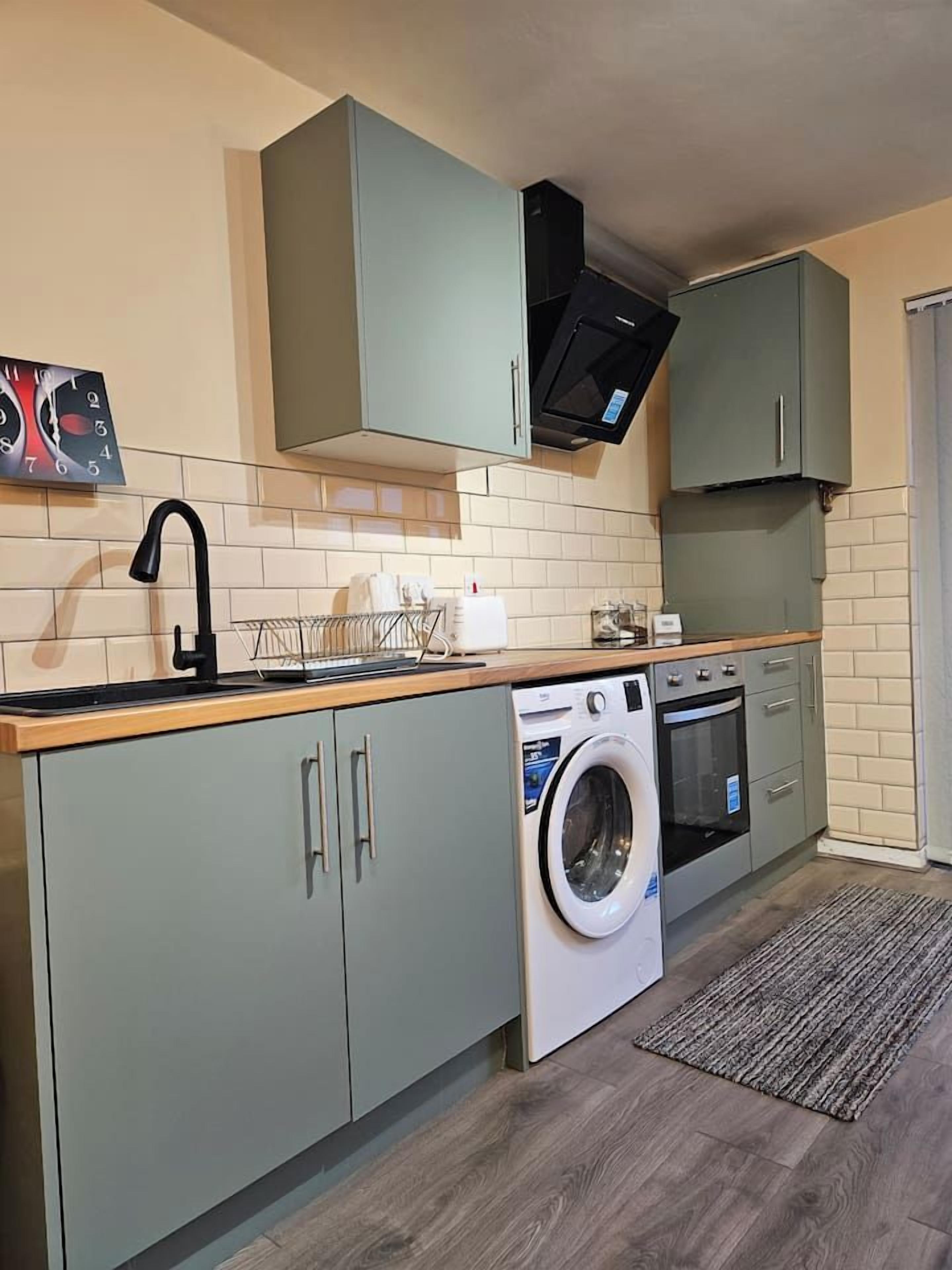 A compact kitchen with a washing machine, a microwave, and a sink.