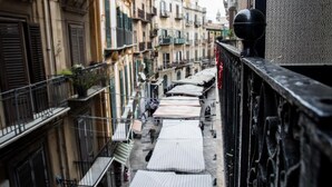 A narrow street with buildings on both sides, featuring balconies and a row of white awnings. - Balate maqueda bnb (Palermo)