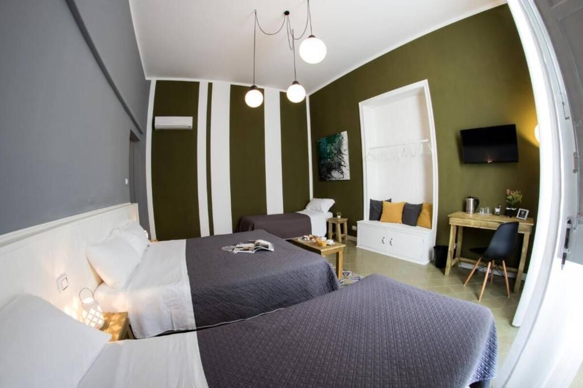 Quarto de hotel moderno com duas camas, uma escrivaninha, uma cadeira, uma televisão e um quadro na parede.