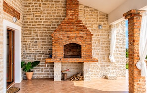 A brick fireplace with a stone wall, a potted plant, and a door.