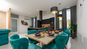 A modern dining area with teal chairs, a wooden table, and pendant lights.