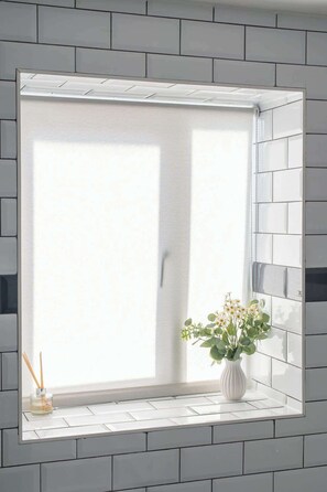 A window with a white frame, a white tiled wall, and a white vase with flowers on a windowsill. - Stylish Luxe Apartment in Crayford (Dartford)