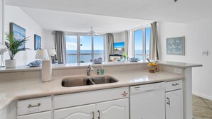 Una cocina moderna con un ventanal grande, un ventilador de techo y vista a la playa.