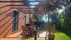 A patio with a pergola, outdoor furniture, and a potted plant. - Apartment Cala Azzurra - with large garden and a stone's throw from the sea (Cavo)