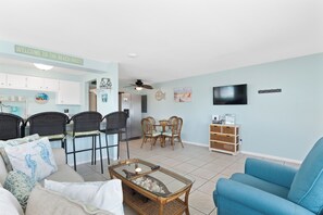 A living room with a sofa, chairs, a coffee table, a TV, and a dining area with chairs and a table. - ☀️ Short Walk to Beach, Perfect for Couples Getaway - Crescent Shore 201 ☀️ (Fort Myers Beach)