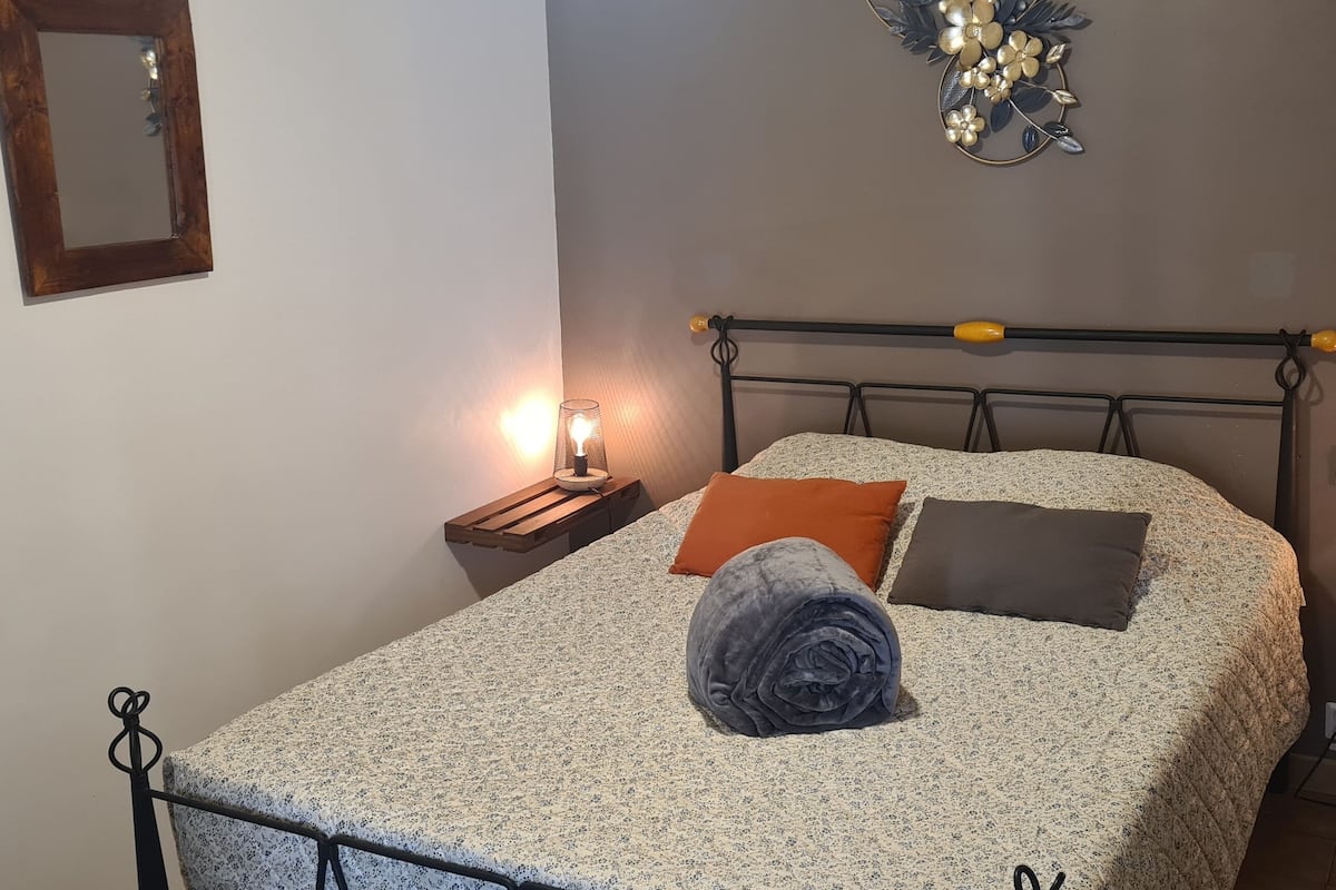 Ein Schlafzimmer mit einem Bett, zwei Nachttischen mit Lampen, einem Spiegel und einem dekorativen Wandbild.