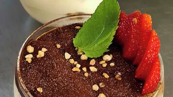Zwei Dessertgläser mit Schokoladenmousse, Erdbeeren und einem Minzblatt auf einer Metalloberfläche.
