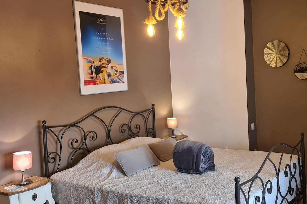 Ein ordentlich eingerichtetes Schlafzimmer mit einem Bett, Nachttischlampen, einem Poster an der Wand und dekorativer Wandkunst.