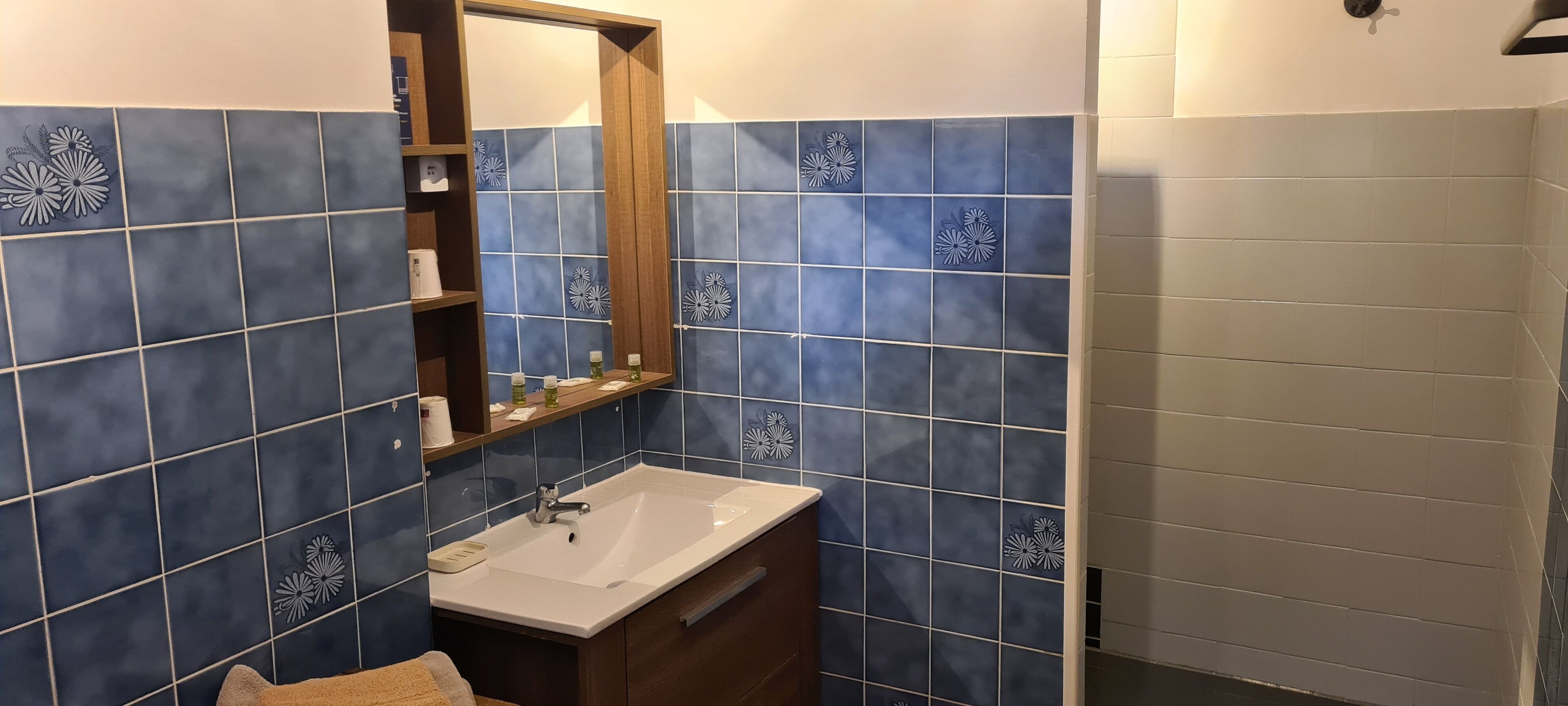 Un baño con lavabo, espejo y repisas con artículos de aseo.