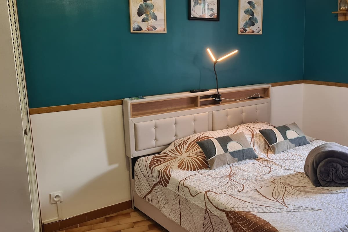 Ein Schlafzimmer mit einem Bett, einem Nachttisch, einer Lampe und einem Kunstwerk an der Wand.