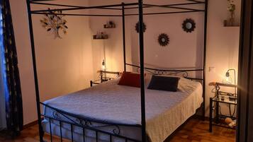 A four-poster bed with a patterned bedspread, two pillows, and bedside lamps.