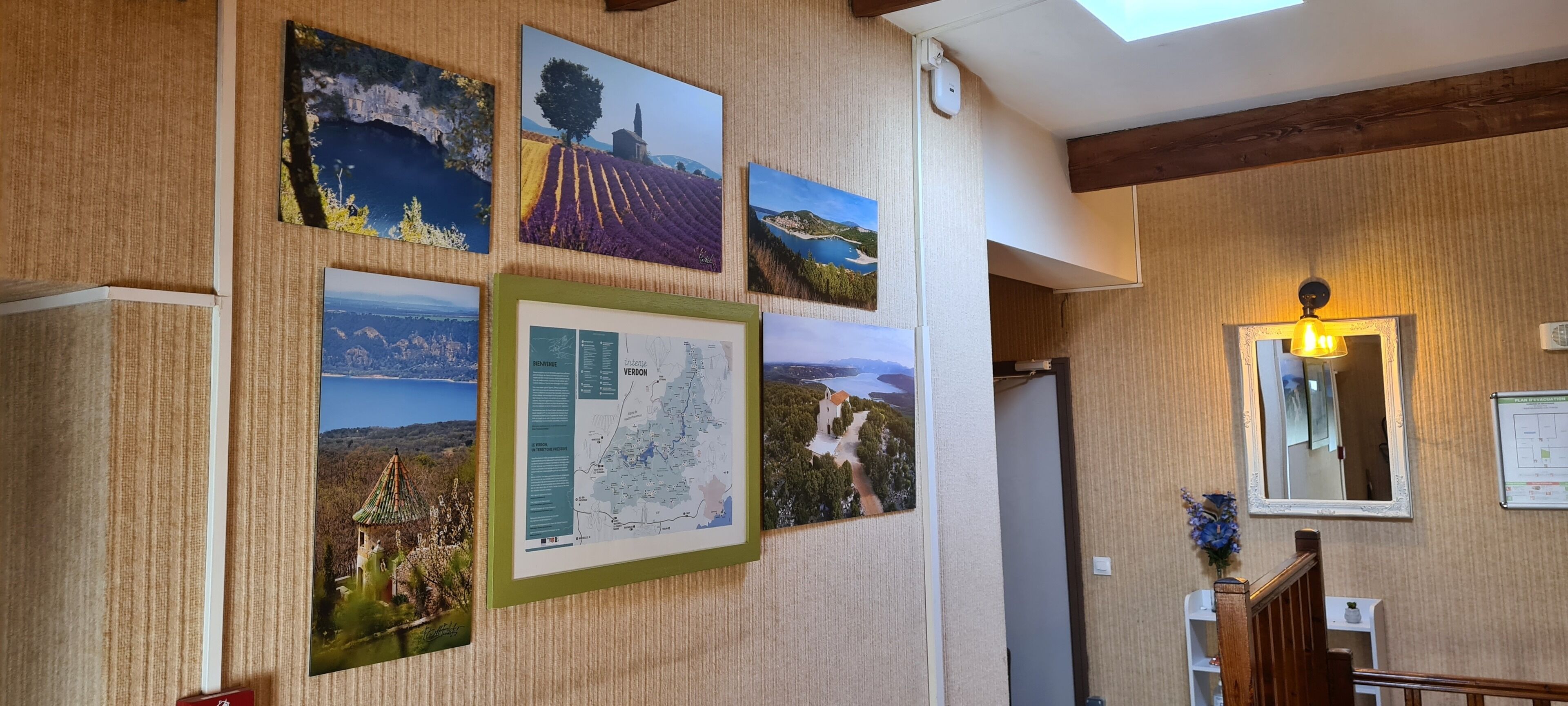 A hallway with framed landscape photographs on the wall, a map, and a mirror.