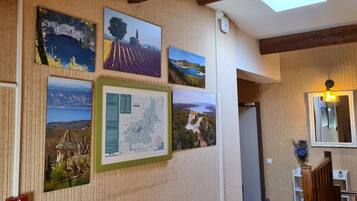 Um corredor com fotografias de paisagens emolduradas na parede, um mapa e um espelho.