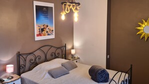 Een netjes opgemaakt bed met een opgerolde handdoek, een poster aan de muur en een decoratieve zon.