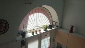 A kitchen with a window, a clock, and various kitchen items. - Cozy studio apartment with loft in San Lorenzo (Roma)