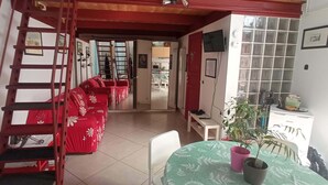 A room with a red sofa set, a dining table with a green tablecloth, and a staircase with a red handrail. - Cozy studio apartment with loft in San Lorenzo (Roma)