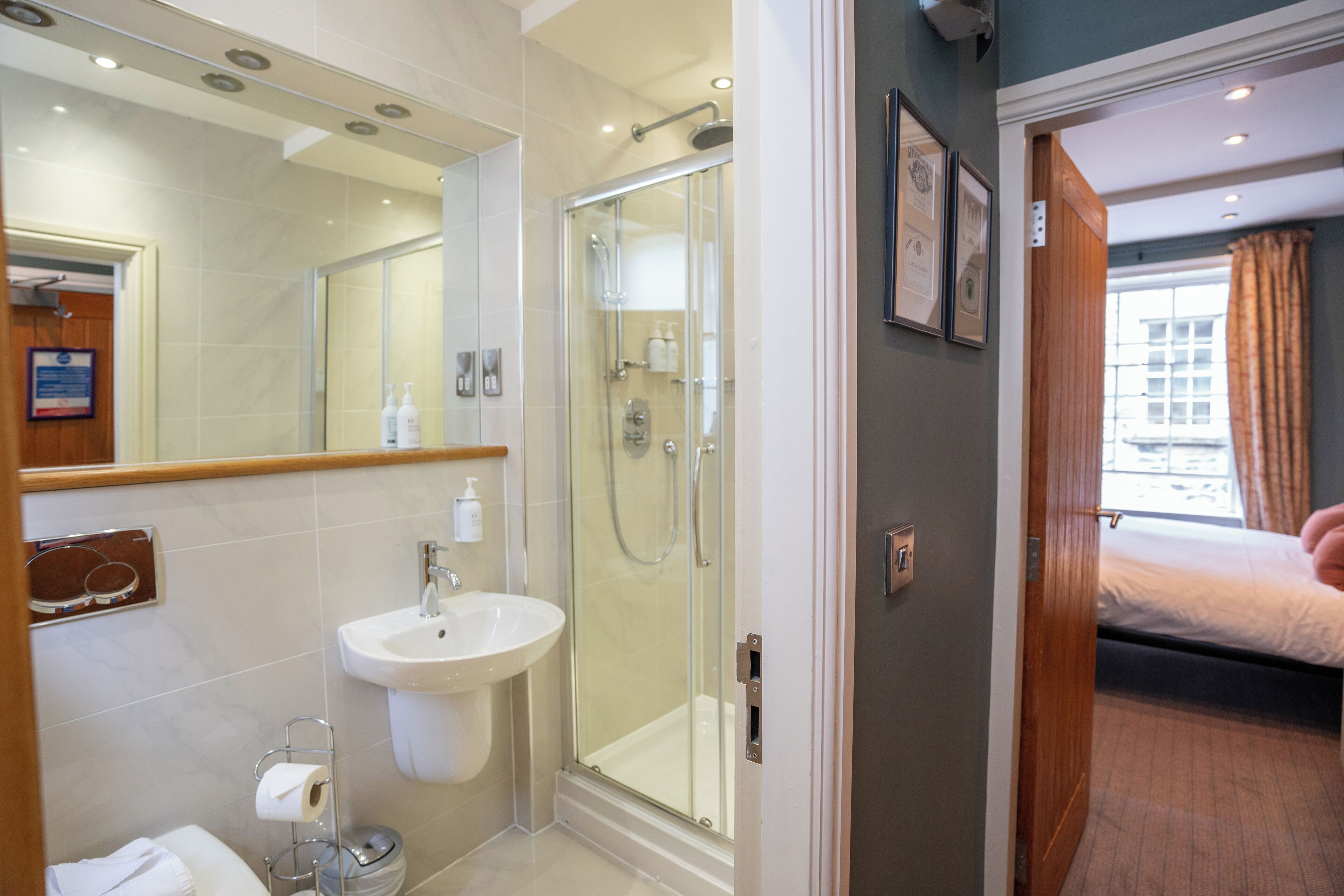 Un baño de hotel con ducha de vidrio, lavamanos y retrete.