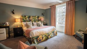 A bedroom with a bed, nightstands, a lamp, a dresser, a chair, and a window with curtains.