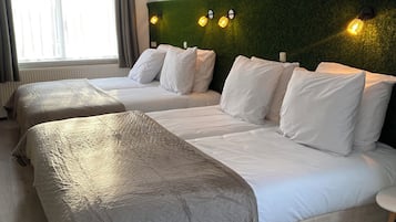 Ein Hotelzimmer mit zwei Betten, einem Deckenventilator und einer grünen Wand mit Wandleuchten.