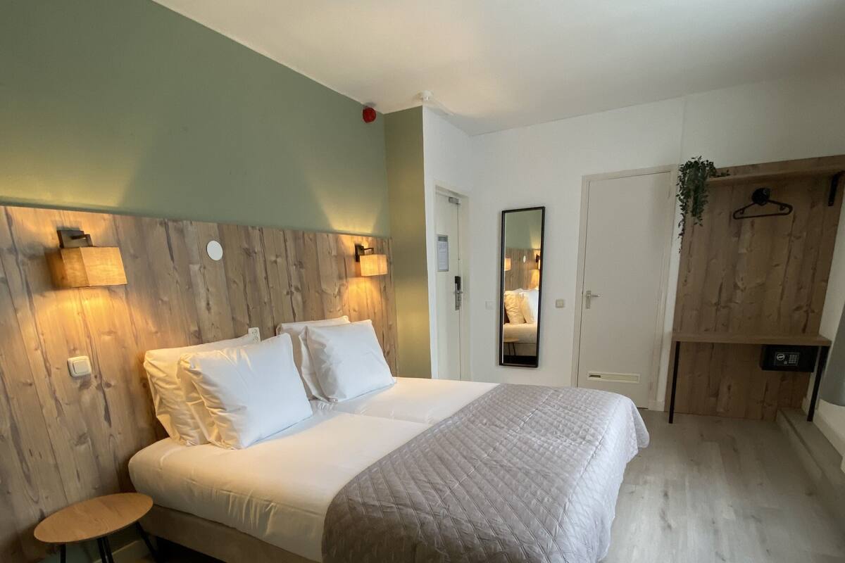 Ein Schlafzimmer mit einem großen Bett, Nachttischen, einem Spiegel und einem Kleiderschrank.