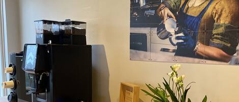 A coffee machine, a wooden box with cards, and a potted plant on a counter.