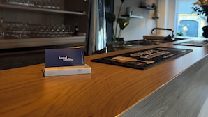 Een bar met een biertappinstallatie, een hotelnaambord en een menukaart.