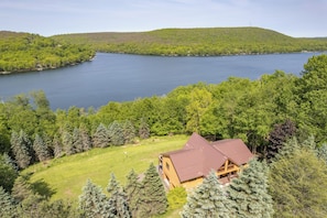 Eine Holzhütte mit braunem Dach, umgeben von dichtem Wald und einem See.