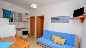 A compact living space with a kitchenette, a dining area, and a sofa. - Coastal Breeze House (Selca)