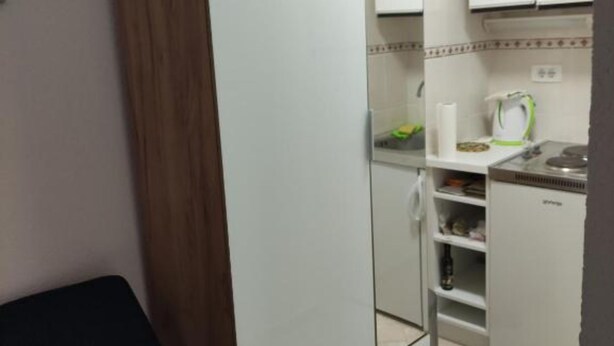 Une cuisine de taille réduite avec des meubles blancs, un petit plan de travail et un réfrigérateur.