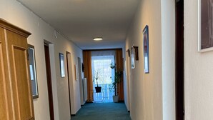 A hallway with a green carpet, wooden doors, and framed pictures on the walls. - Pension Plattenhof  (Telfs)