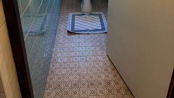 A small bathroom with a toilet, a window, and patterned tiles.