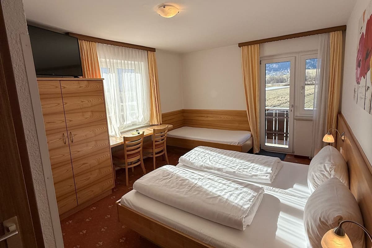 A hotel room with a bed, a desk, and a TV.