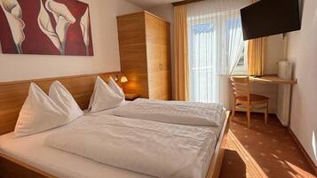 Una habitación de hotel con una cama grande, un escritorio con una silla, un televisor y un cuadro en la pared.