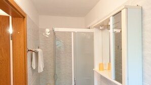 Un baño moderno con cabina de ducha de vidrio, un lavabo blanco y un espejo sobre él.
