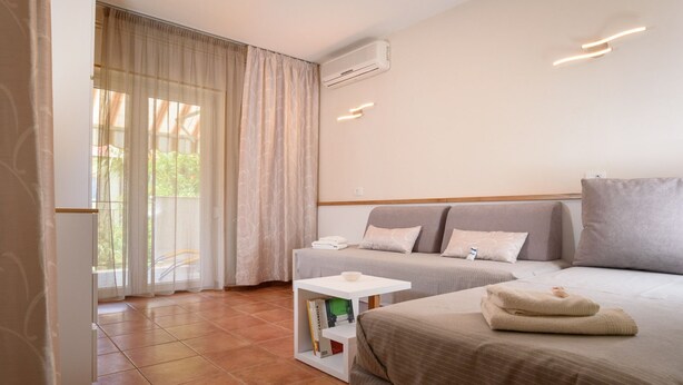 Habitación de hotel con una cama, dos mesitas de noche, una pequeña mesa blanca y una estantería.