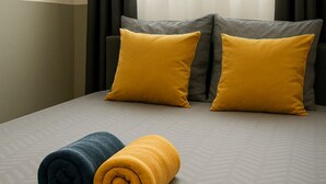 A hotel room with a bed, two pillows, and two rolled towels. - Studio SABLE & MER (Merville-Franceville-Plage)