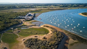 An aerial view of a coastal area with a river, boats, and a mix of natural and developed land. - Studio SABLE & MER (Merville-Franceville-Plage)