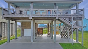 A two-story wooden deck with a covered upper level, outdoor seating, and a staircase. - Abigail's House, 3 bedroom 2 bath home sleeps10. A short stroll to the beach. (Crystal Beach)