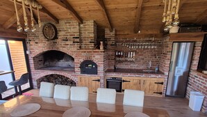 Eine rustikale Küche mit Backofen aus Ziegelsteinen, Holzschränken und einem Edelstahlkühlschrank.