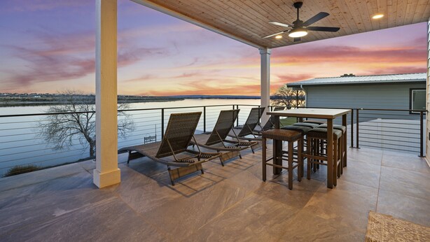 A covered patio with a view of a lake, featuring lounge chairs and a table. - Beautiful Lakefront Home with Spa and 6 Bedrooms! (Moses Lake)