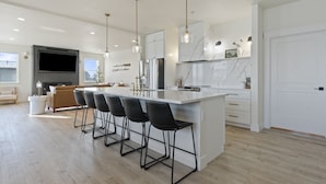 A modern kitchen with a large island, bar stools, and a flat-screen TV. - Beautiful Lakefront Home with Spa and 6 Bedrooms! (Moses Lake)