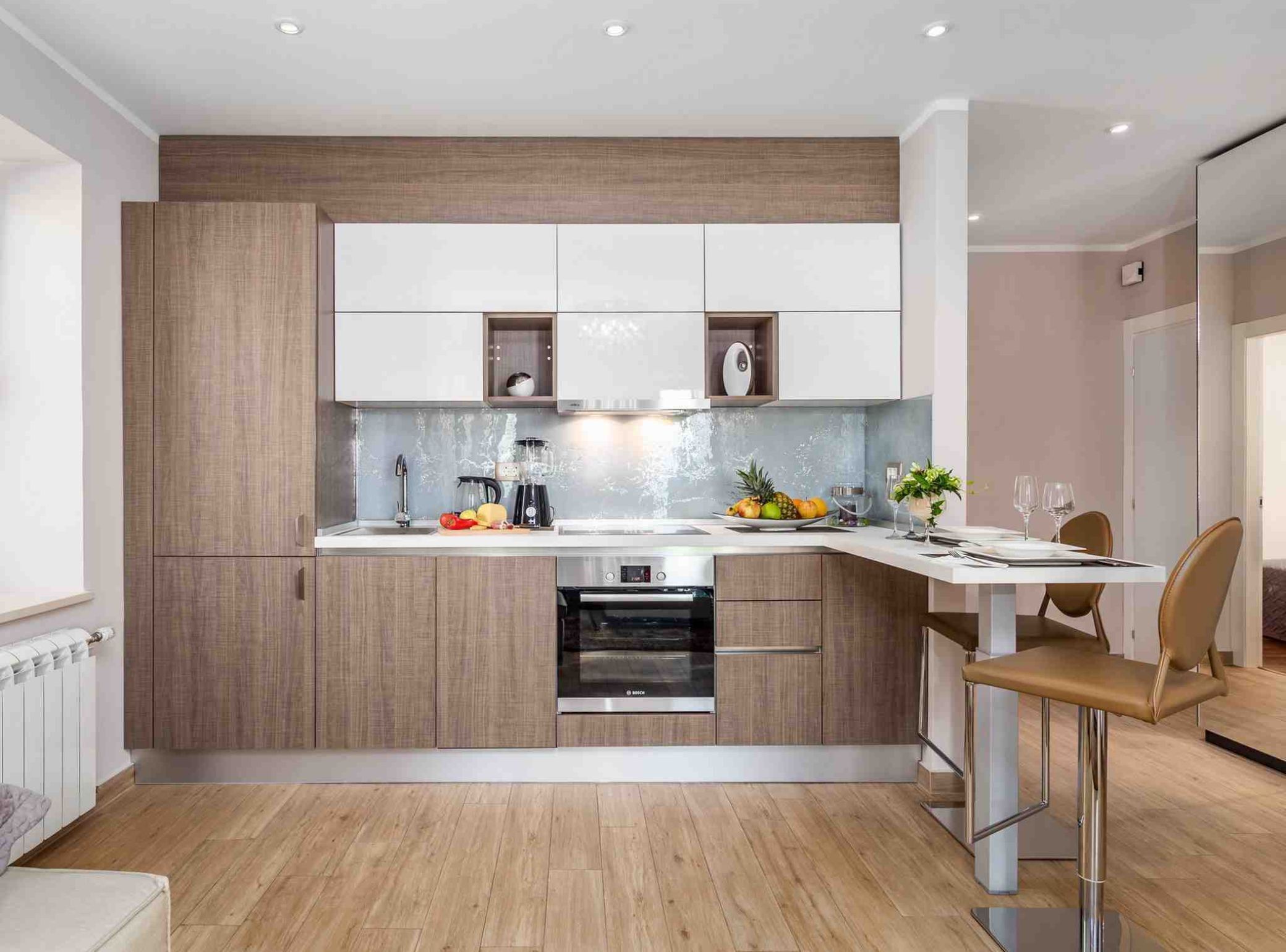 A modern kitchen with a built-in oven, a coffee machine, and a fruit bowl on the counter.