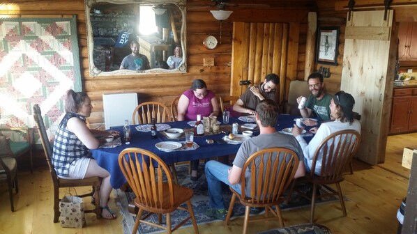 A wooden cabin dining area with a table set for six people, surrounded by wooden chairs. - CopperLine Lodge (Saratoga)