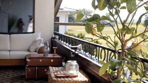 Een balkon met een rieten tafeltje, een koffer en een bloempot.