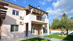 A two-story house with a balcony, a swimming pool, and a well-maintained lawn. - Apartment Villa Troskot (Pirovac)