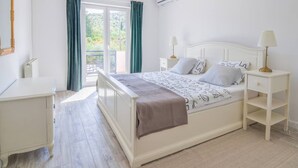 A bedroom with a bed, bedside tables, a dresser, a mirror, and a window with curtains. - Apartment Villa Troskot (Pirovac)